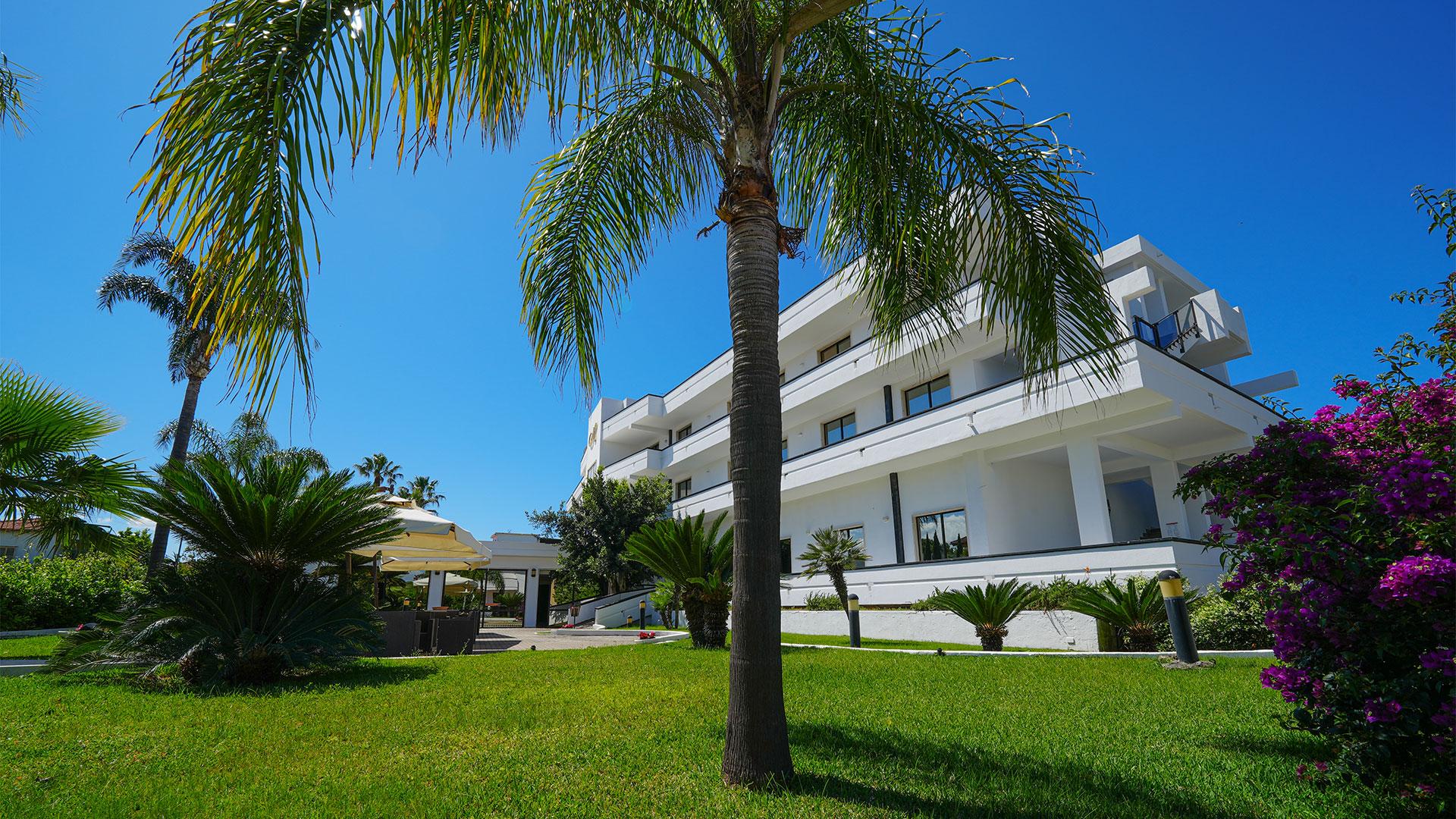 Edificio moderno con giardino tropicale, palme e cielo azzurro.